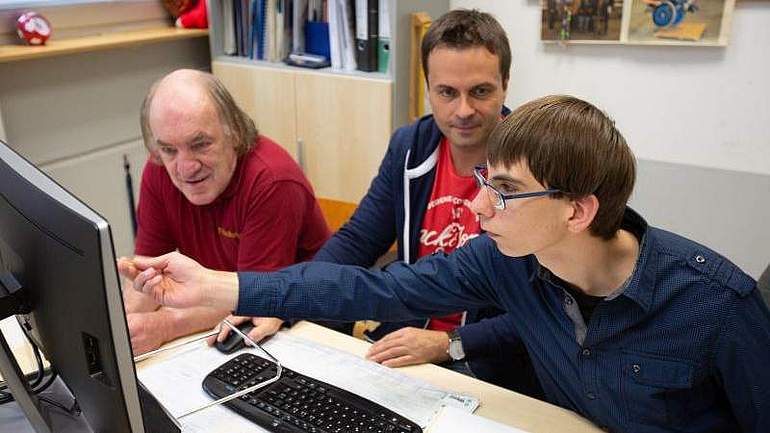 Drei Männer, die zusammen auf einen Computer-Bildschirm schauen