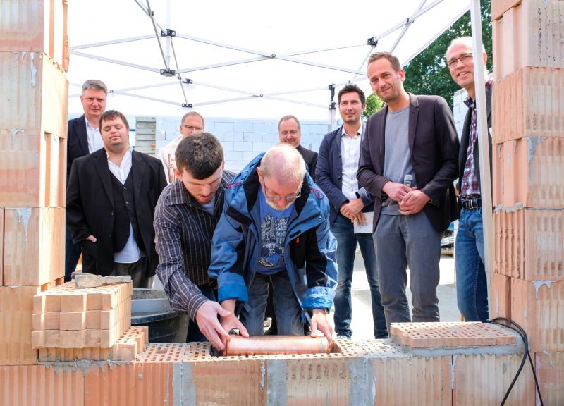 Die Verantwortlichen mauern ein Zeitkapsel bei der Grundsteinlegung ein