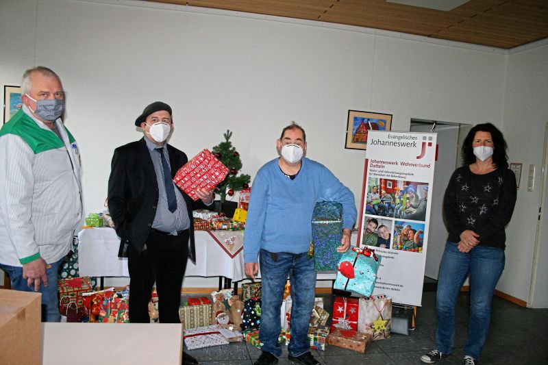 Vier Personen mit Maske und bunt verpackten Geschenkpaketen