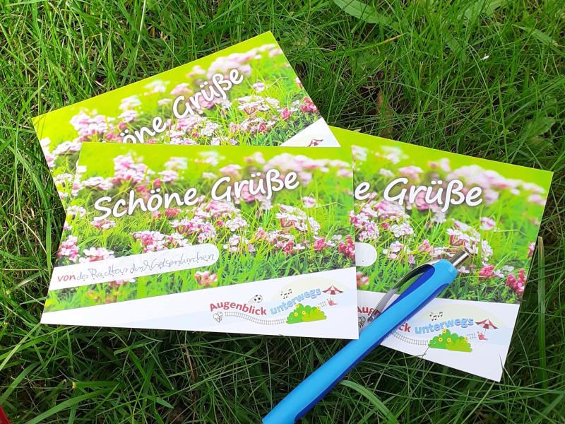 Grüße von der Radtour Drei Postkarten liegen auf einer Wiese