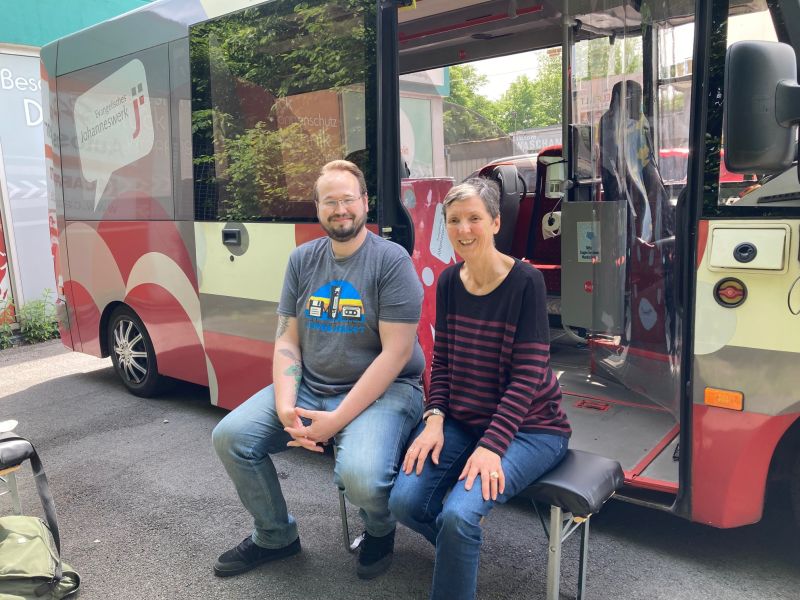 Ein Mann und eine Frau sitzen vor dem Jo-Mobil-Bus