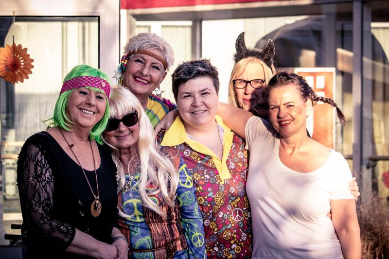 Sechs verkleidete Frauen halten sich im Arm und feiern gemeinsam Karneval