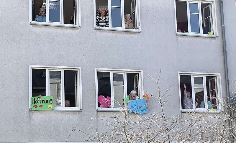 Bewohnerinnen und Bewohner des Karl-Pawlowski-Altenzentrums freuen sich an offenen Fenstern über Abwechslung durch das Programm der Innenhof-Begegnungen 