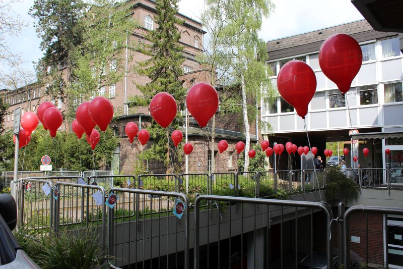 Bitte mitnehmen und besondere Augenblicke verschenken - dazu laden die roten Luftballons mit den Wunschkarten am Zaun vor dem Johannes-Haus in Herford ein