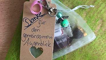 Danke für den gemeinsamen Augenblick Ein Schild mit Danke und ein kleiner Engel sind an ein mit Süßigkeiten gefülltes Beutelchen gebunden