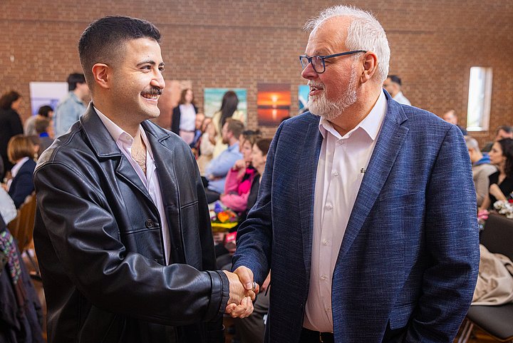 Geschäftsführer Dr. Bodo de Vries gratuliert dem Absolventen Cem Eraslan.