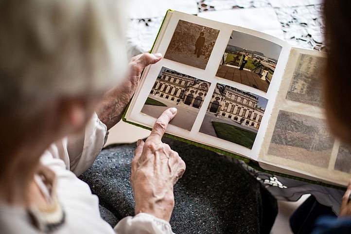 Alter Dame sieht sich ein Fotoalbum mit Sepiafotos an.