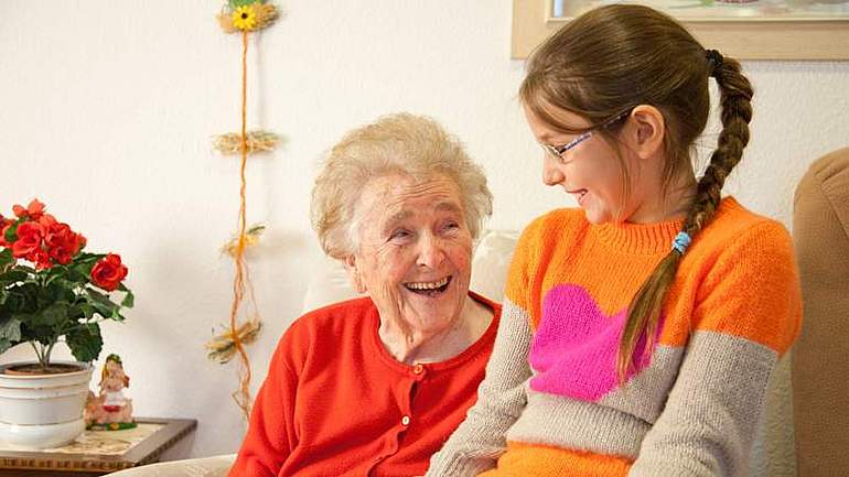 Mädchen sitzt bei Oma auf dem Schoß