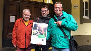 Drei Männer stehen nebeneinander und haben die Urkunde zum Klimaschutzpreis in der Hand