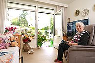 Bewohnerin sitzt in einem Sessel in ihrem Zimmer