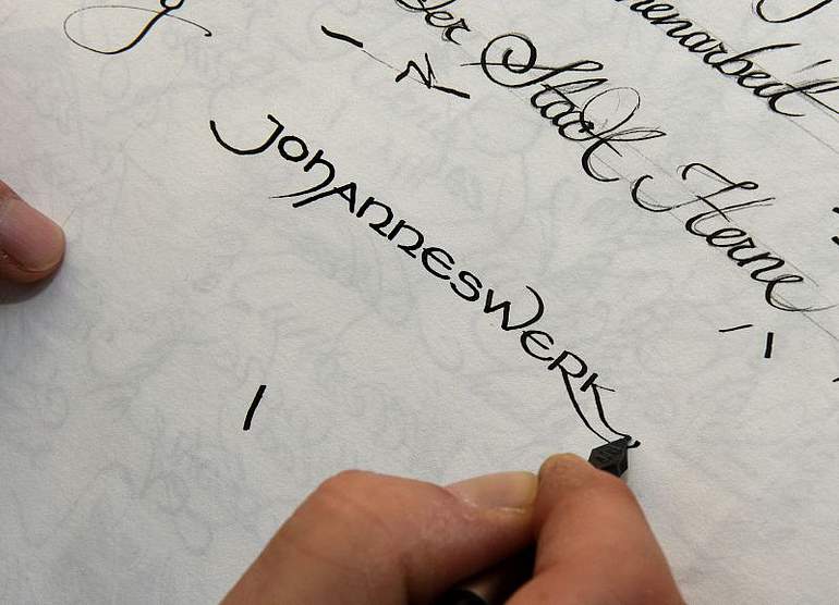 "Johanneswerk" mit schwarzer Tinte kalligrafiert auf weißem Papier.