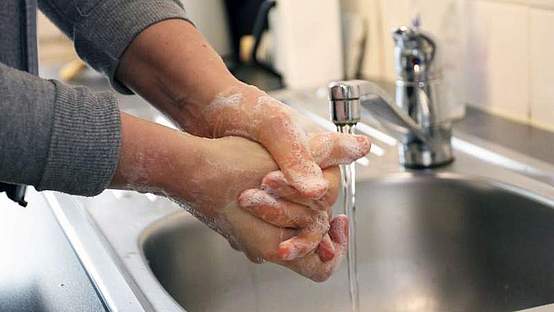 Hände, die über einem Spülbecken gewaschen werden.