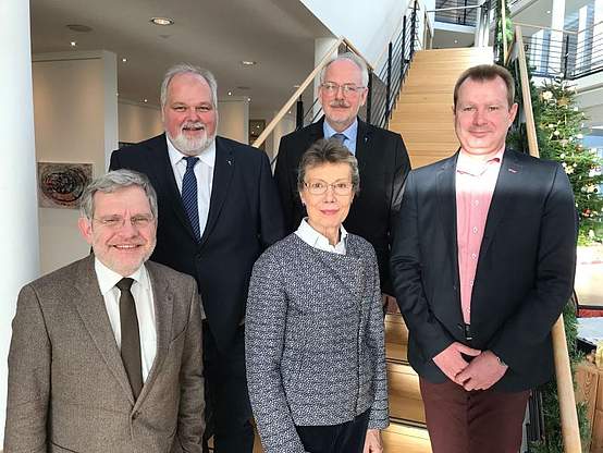 Fünf Personen auf einer Treppe lächeln in die Kamera.