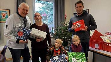 3 Erwachsene und zwei Kindern mit bunt verpackten Geschenken