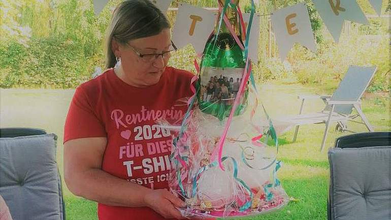 Eine Frau mit rotem T-Shirt hält ein Geschenk in der Hand