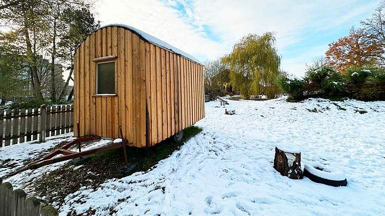 Ein Bauwagen aus Holz, der im Garten der Kita Sonnenblume steht