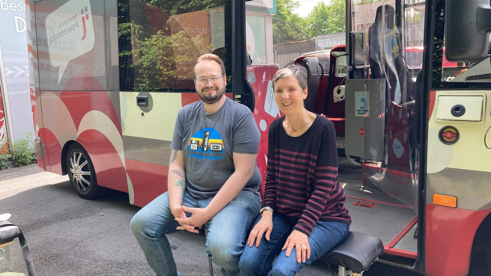 Zwei Menschen sitzen vor dem Jo-Mobil-Bus