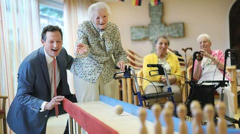 Ein Mann und eine alte Frau spielen zusammen Tischkegeln.