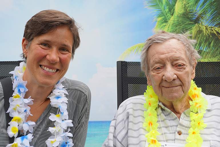 Zwei Frauen haben eine Hawaii-Kette um und lächeln in die Kamera