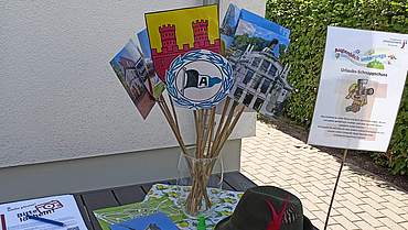 Reise durch Bielefeld im Marswidisstift Fotos von Bielefelder Sehenswürdigkeiten sind an einem Holzstab angeklebt