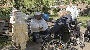 Ein Imker erklärt Kindern und Senioren den Umgang mit Bienen