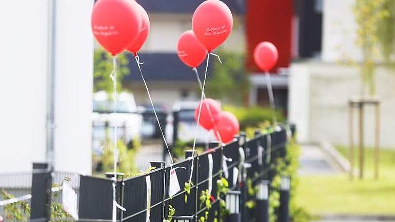 Rote Luftballons, die an einem Gartenzaun hängen