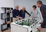 Mehrere Menschen, die gemeinsam Kicker spielen