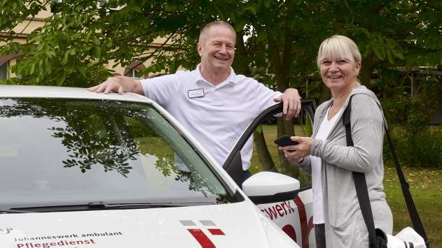 Ein Mann und eine Frau, die an einer geöffneten Autotür stehen