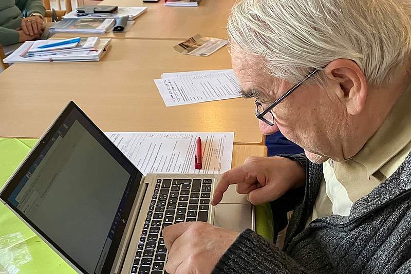 Ein alter Mann tippt an einem Laptop