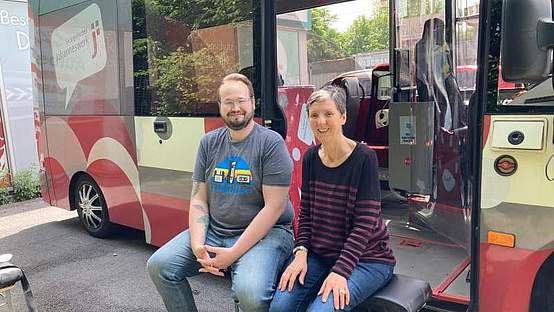 Ein Mann und eine Frau sitzen vor dem Jo-Mobil-Bus