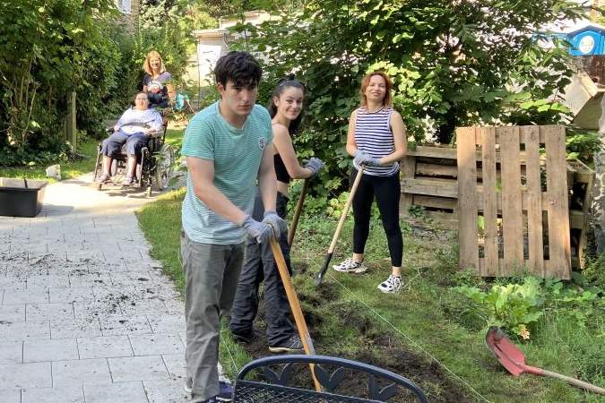 Klient*innen schauen bei dem Ausbau des Hühnergeheges zu Klient*innen beobachten die Veränderungen im Garten des tagesstrukturierenden Angebots