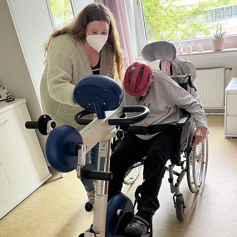 Nina-Sophie Blome hilft einer Bewohnerin im im Rollstuhl beim täglichen Training.