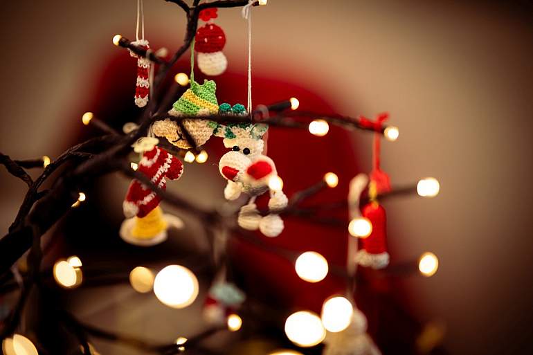 Ein Ast, an dem eine Lichterkette und Weihnachtsdeko hängen