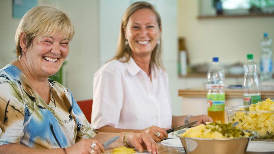 Zwei Frauen, die zusammen in der Küche stehen und einen Kartoffelsalat zubereiten