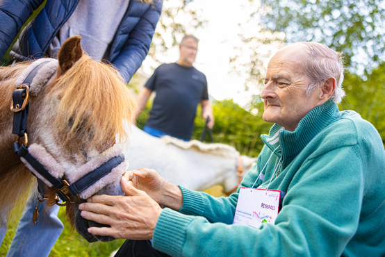 Ein alter Mann streichelt ein Pony